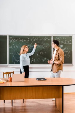 Kadın öğretmen öğrenciye sınıf denklemler işaret