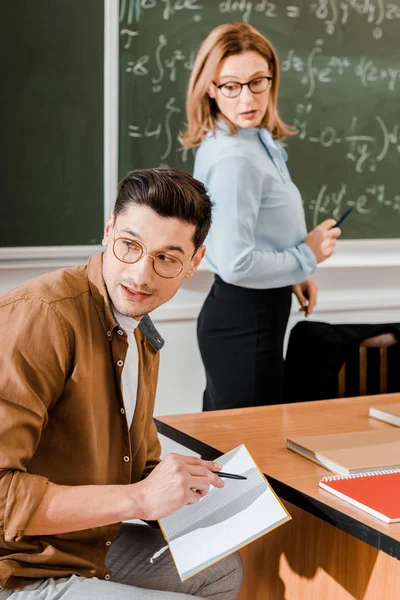 Ung Student Tittar Bort Och Hålla Anteckningsbok Med Penna Nära — Stockfoto