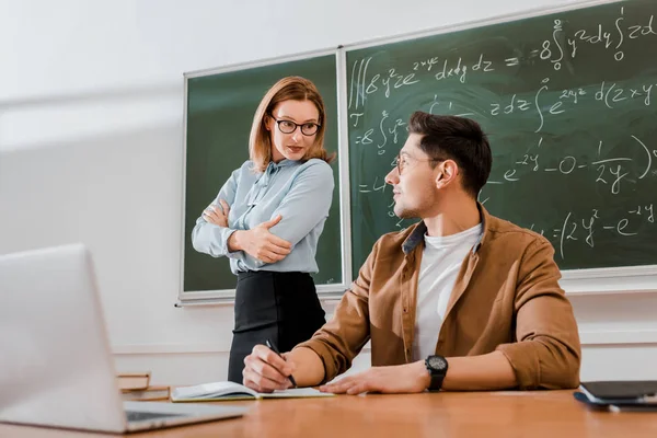 Profesora Pie Con Los Brazos Cruzados Mirando Estudiante Aula — Foto de stock gratuita