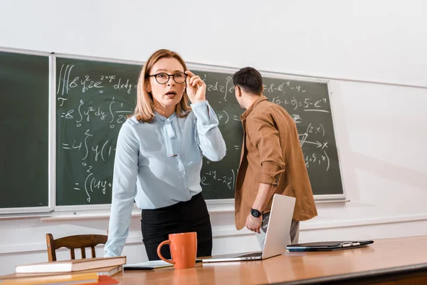 Profesora Pie Cerca Escritorio Mirando Sorprendida Cerca Estudiante — Foto de stock gratuita