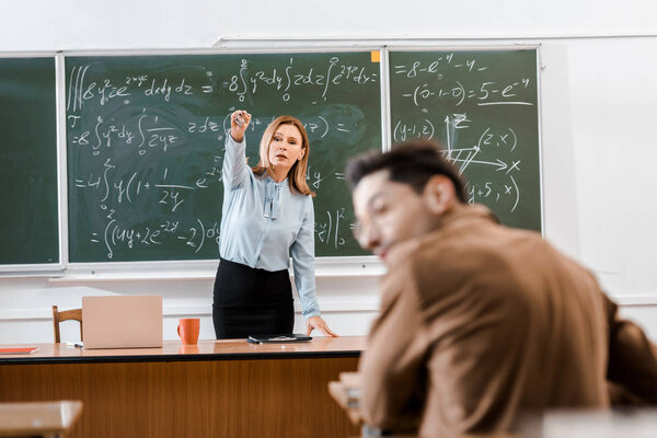 Selective focus of teacher showing something to student 