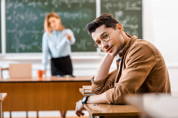 Selective focus of young student in glasses sitting at desk 