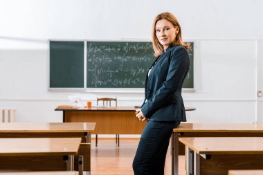 güzel ciddi kadın öğretmen sınıfta kamera bakarak resmi aşınmaya