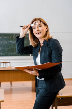 formal giyim ve gözlük sınıfta defter tutan güzel gülümseyen kadın öğretmen