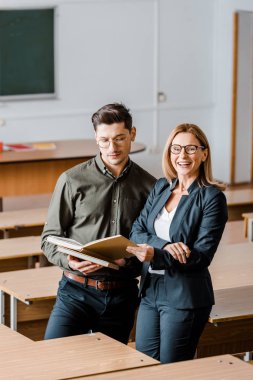 Erkek öğrenci ve gülümseyen kadın öğretmen sınıfta Üniversitesi kitaplar holding