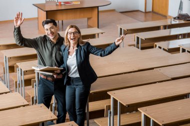 neşeli erkek öğrenci ve Bayan öğretmen sınıfta Üniversitesi kitaplar holding uzanmış eller ile