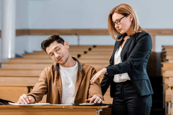 Professora Universitária Olhando Para Estudante Sexo Masculino Óculos Exame Escrita — Fotografia de Stock