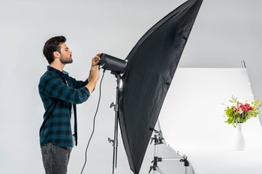 yakışıklı genç fotoğrafçı ekipman fotoğraf stüdyosunda güzel çiçekler çekerken aydınlatma ile çalışma 