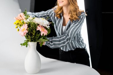 gülümseyen genç kadın çiçek fotoğraf Studio düzenliyor in atış kırpılmış