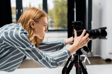 side view of young female photographer working with professional photo camera in studio    clipart