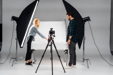 young photographers working with professional equipment in photo studio clipart