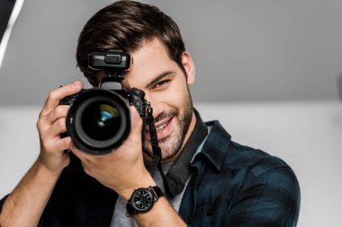 handsome happy young man photographing with camera in studio 