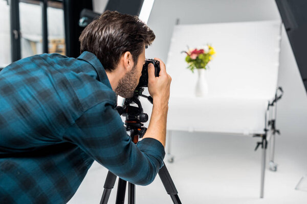 young man photographing beautiful flowers in professional photo studio  