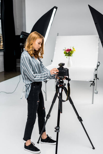 beautiful young female photographer shooting flowers in photo studio