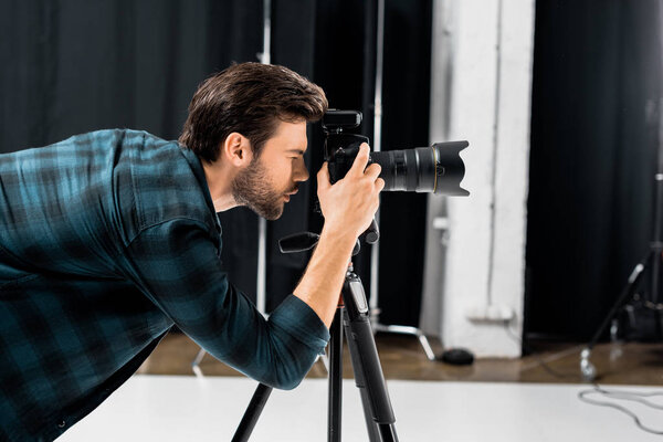 side view of professional young photographer working with camera in photo studio