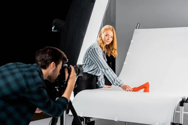 Male Photographer Working Camera While Colleague Arranging Shoe Studio — Stock Photo, Image