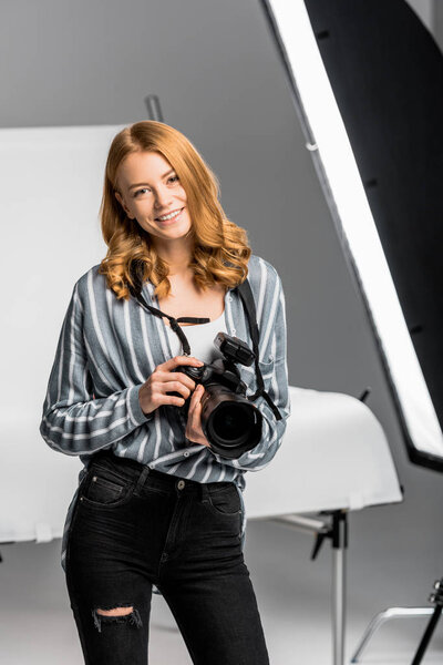 beautiful young female photographer smiling at camera in photo studio