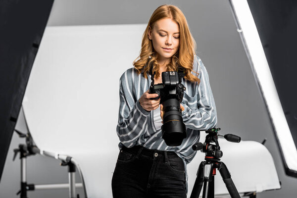 красивая молодая женщина с помощью фотокамеры в студии
