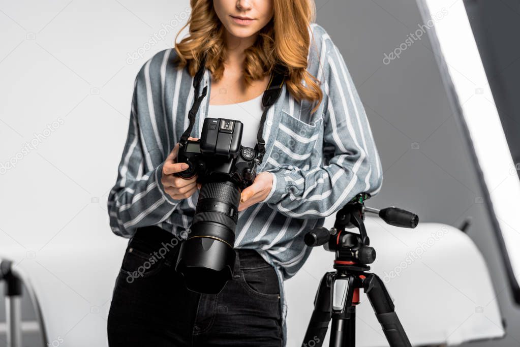 cropped shot of beautiful young woman using professional photo camera in studio