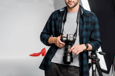 profesyonel genç fotoğrafçı fotoğraf stüdyosunda kamera tutarak atış kırpılmış 