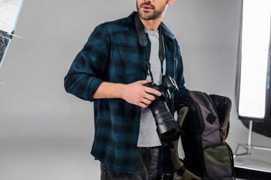 Kırpılan atış fotoğraf makinesi Studio ile ayakta profesyonel genç fotoğrafçı