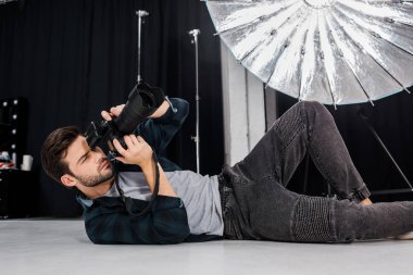yalan ve fotoğraf makinesi Studio'yu kullanarak yakışıklı genç fotoğrafçı