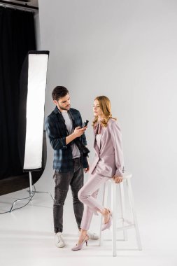 ışığı ölçer tutarak ve güzel kadın modeli Studio ile çalışan genç fotoğrafçı
