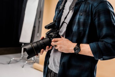 genç fotoğrafçı fotoğraf stüdyosunda kamera tutarak kırpılmış atış
