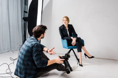 Kamera ve fotoğraf stüdyosunda konuşan genç modeli ile fotoğrafçı