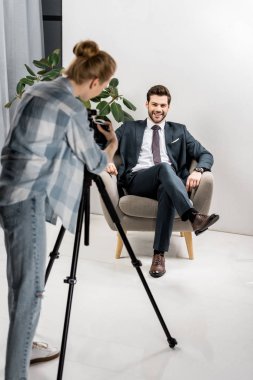 arkadan genç fotoğrafçı ofiste yakışıklı gülümseyen işadamı fotoğraflarını görünüşü