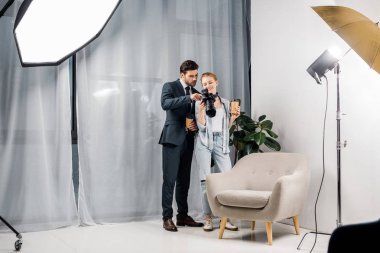 kadın fotoğrafçı ve kağıt bardak tutan ve fotoğraf Studio fotoğraf makinesi üzerinde denetimini genç işadamı