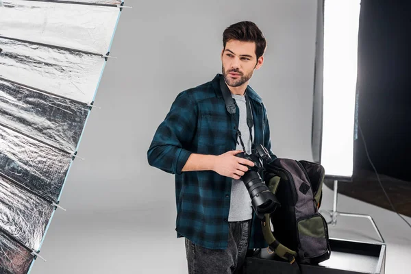 Handsome Professional Young Photographer Standing Photo Camera Looking Away Studio — Free Stock Photo