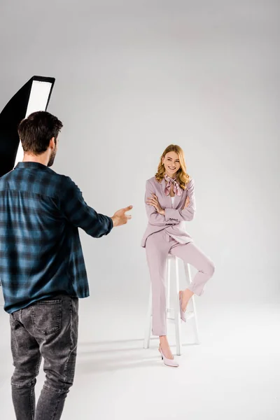 back view of young photographer talking with beautiful smiling female model in studio