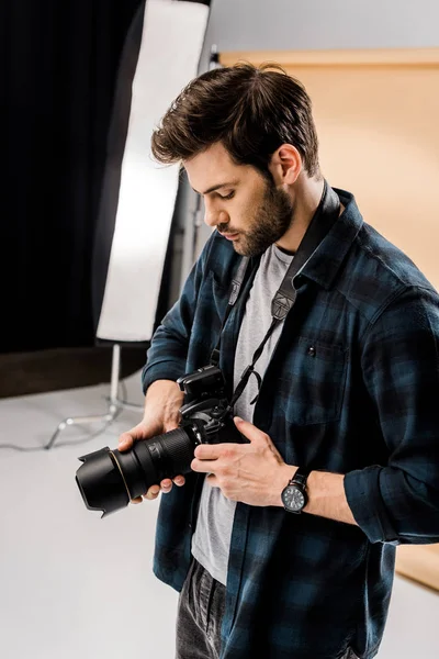 英俊的年轻摄影师使用相机在照相馆 — 图库照片