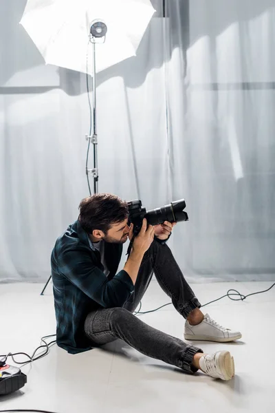 スタジオで写真を撮るプロのカメラでハンサムな若いカメラマン  — 無料ストックフォト