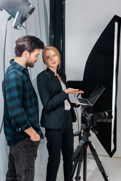 Fotograf Modelu Pomocą Laptopa Patrząc Siebie Studio Fotograficzne — Darmowe zdjęcie stockowe