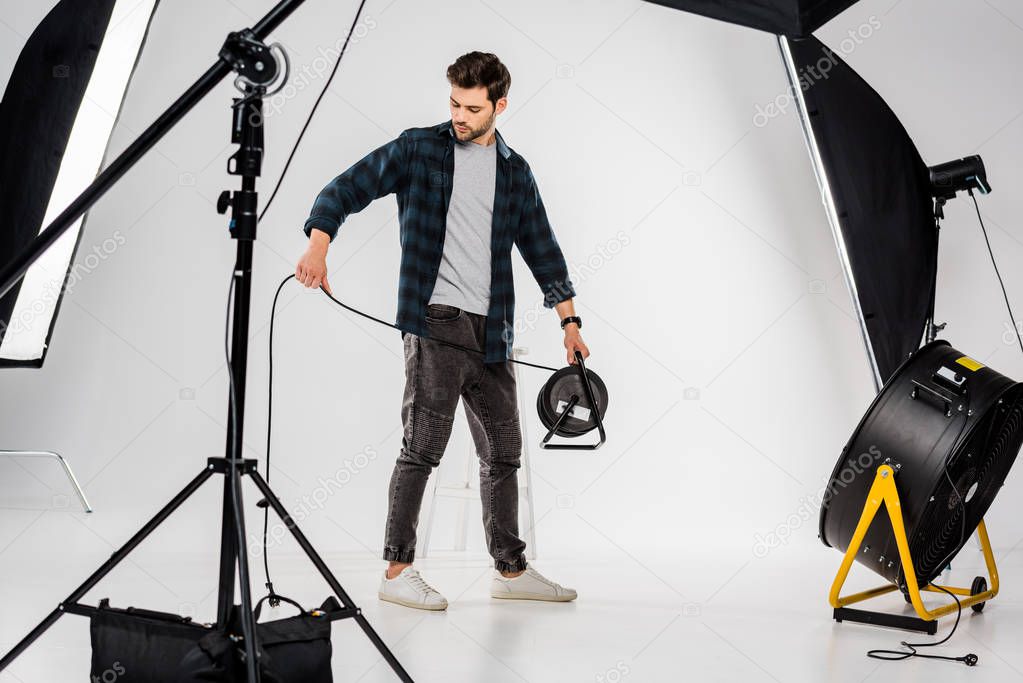 young photographer working with equipment in professional photo studio  