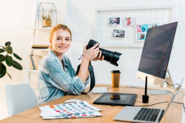 ofiste çalışırken kameraya gülümseyen güzel genç kadın fotoğrafçı