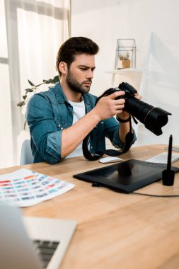 yakışıklı genç fotoğrafçı işyerinde kamera kullanarak  