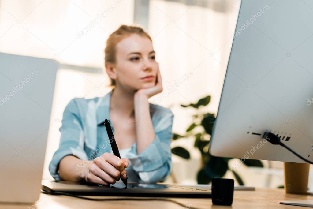 close-up view of young retoucher using desktop computer and drawing tablet in office 