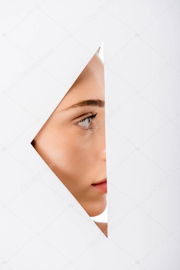 profile of beautiful young woman looking away, view through hole on white