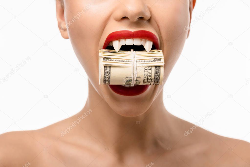 cropped shot of naked girl with vampire teeth holding rolled dollars in mouth isolated on white