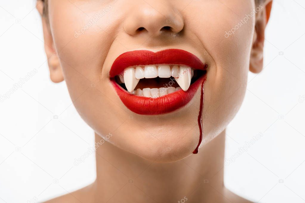 cropped shot of girl with red lips, vampire fangs and blood on face isolated on white