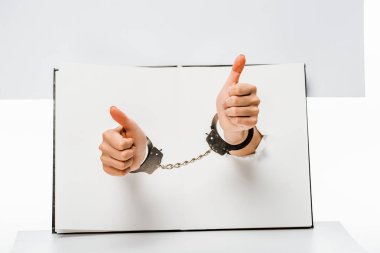 beyaz üzerine deliklerden başparmak gösterilmesini kelepçeli erkek kısmi görünümünü eller 