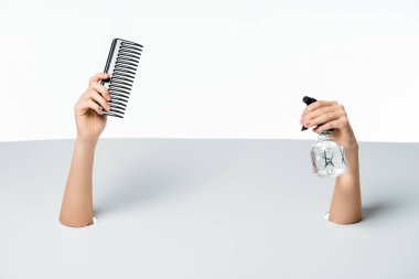 cropped shot of woman holding comb and spray bottle through holes on white clipart