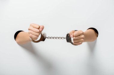 cropped image of girl in handcuffs holding hands through holes on white clipart