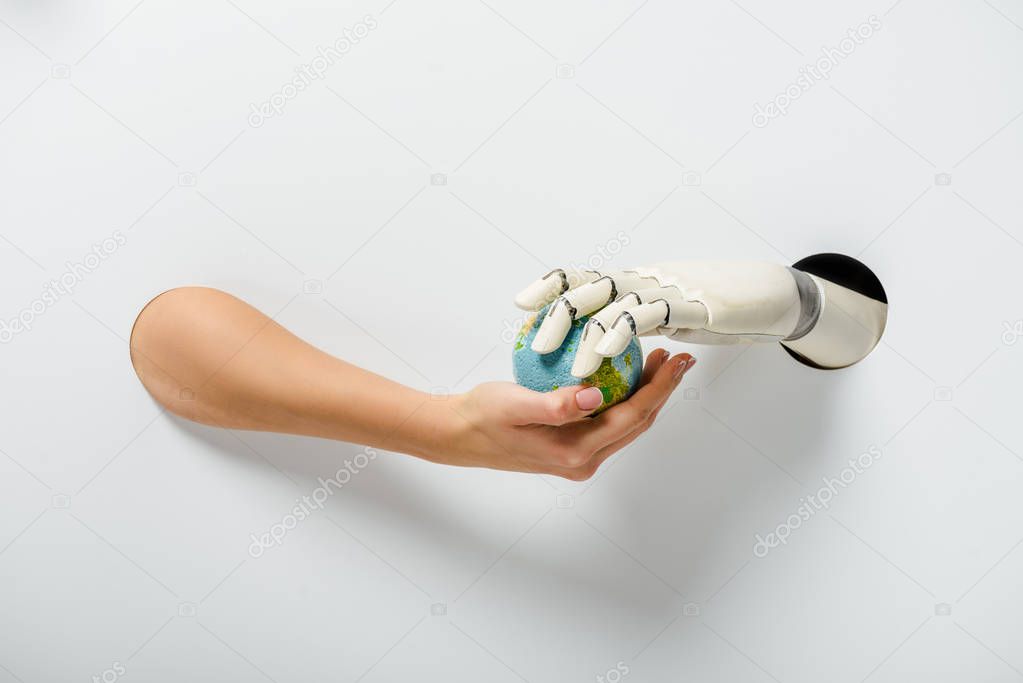 cropped image of woman with hand prosthesis holding earth model through holes on white