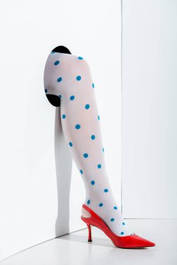 cropped image of girl showing leg in stylish white tights with blue dots and red high heel in hole on white clipart