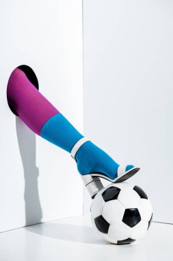 cropped image of girl putting leg in stylish violet tights, blue sock and white high heel on football ball through hole on white clipart