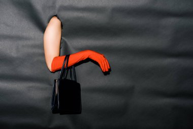 cropped image of girl showing hand in stylish orange glove and black handbag through black paper clipart